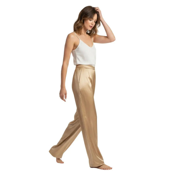 Mannequin en mouvement portant un pantalon en soie dorée et un body blanc léger