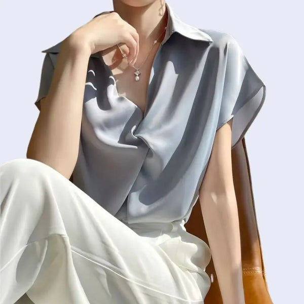 Mannequin assis portant un chemisier ample manches courtes en satin mat bleu ciel