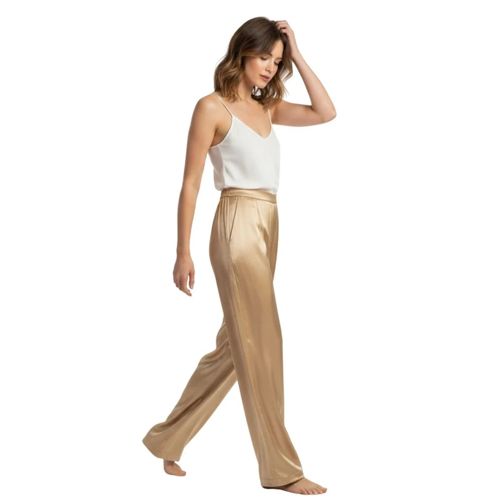 Mannequin en mouvement portant un pantalon en soie dorée et un body blanc léger