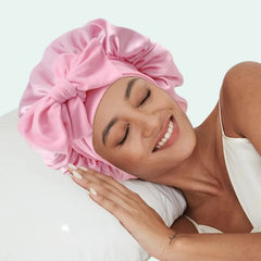 Modèle sur un coussin portant un bonnet de nuit brillant extensible en satin rose