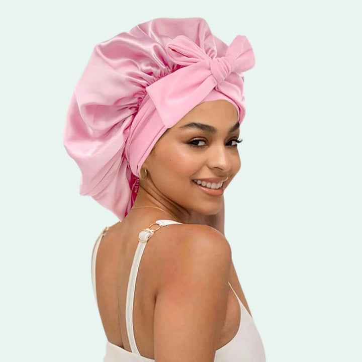 Modèle de profil portant un bonnet de nuit brillant extensible en satin rose