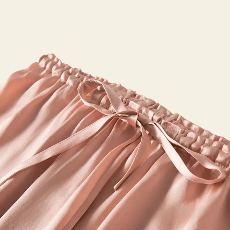 Zoom sur le haut d'un ensemble peignoir et pantalon rose en soie de mûrier