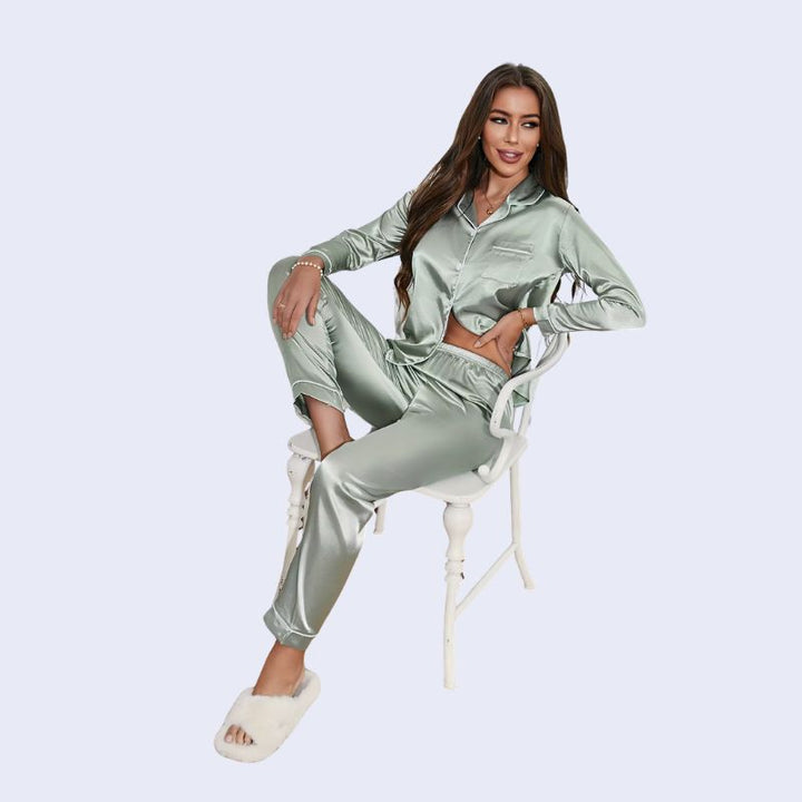 Mannequin assis portant un ensemble pyjama chemisier long boutonné et pantalon en satin brillant couleur vert celadon