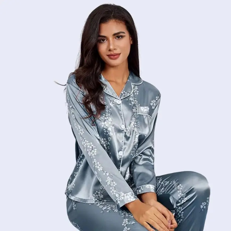 Mannequin assis portant un ensemble pyjama chemisier long et pantalon motifs floraux en satin couleur bleu acier