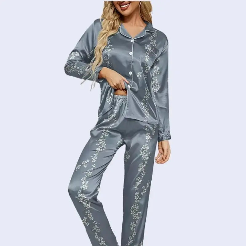 Mannequin blonde portant un ensemble pyjama chemisier long et pantalon motifs floraux en satin couleur bleu acier