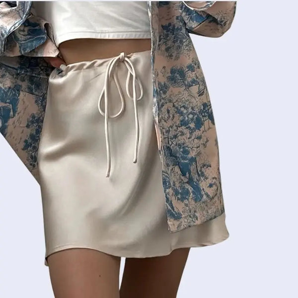 Modèle portant une jupe courte brillante à cordon ajustable en satin couleur ivoire