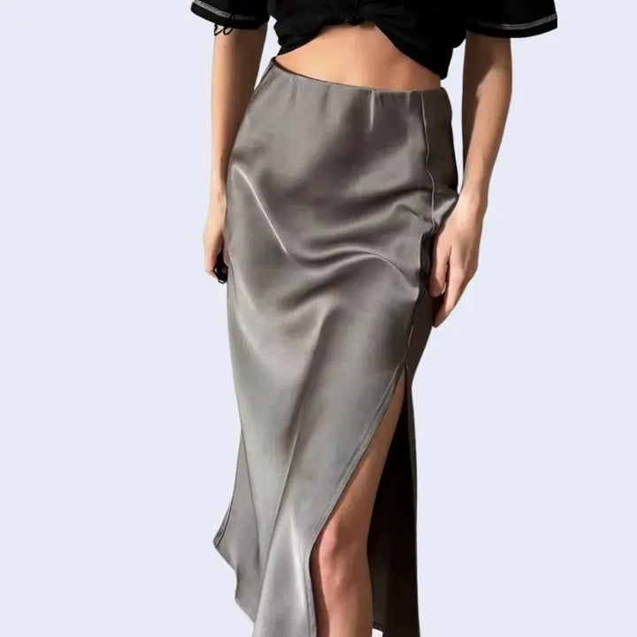 Modèle montrant la fente d'une jupe mi-longue unie en satin couleur grise