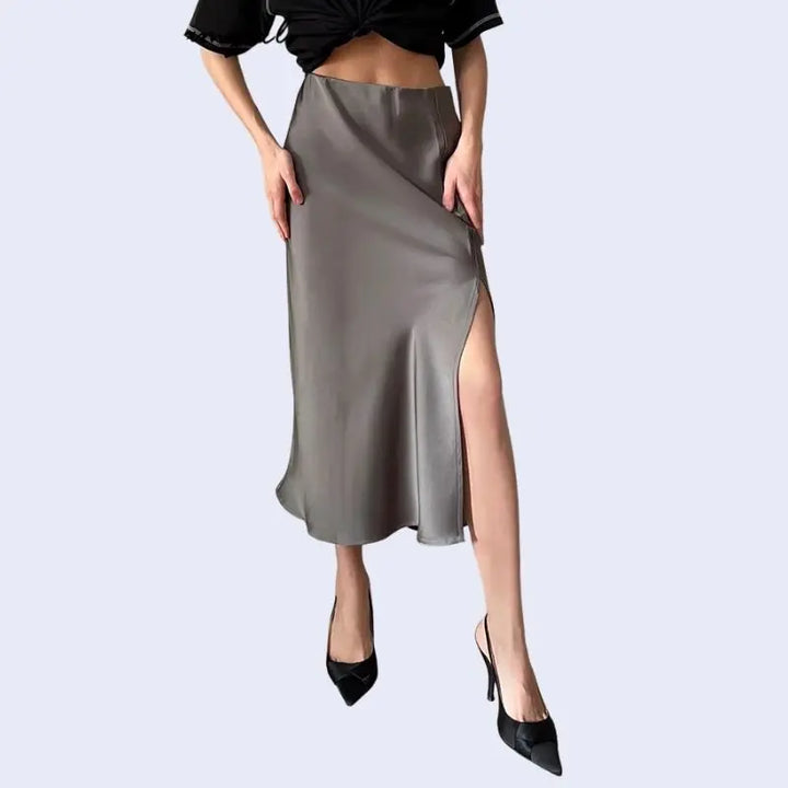Modèle de léger profil portant une jupe mi-longue unie avec fente latérale en satin couleur grise