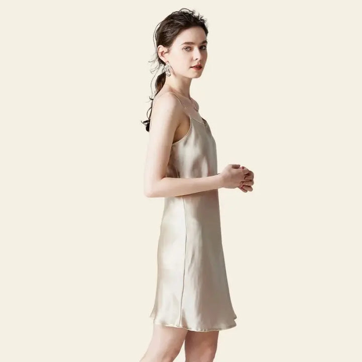 Modèle de profil portant une mini-robe brillante à bretelles fines 100% soie couleur champagne