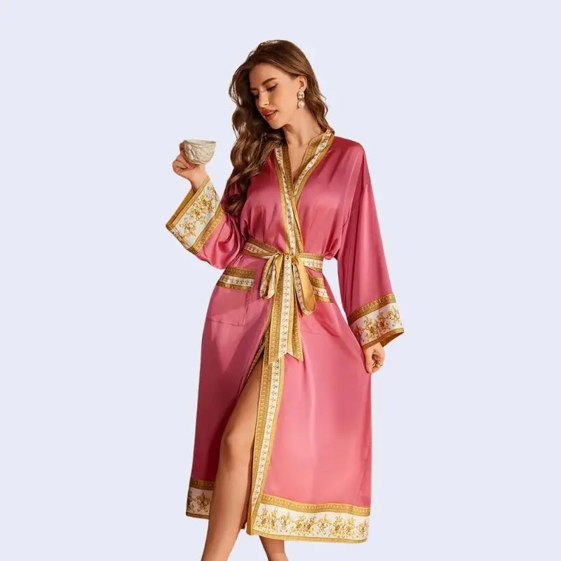 Mannequin portant un peignoir oriental avec motifs dorés en satin couleur rose avec une tasse de café