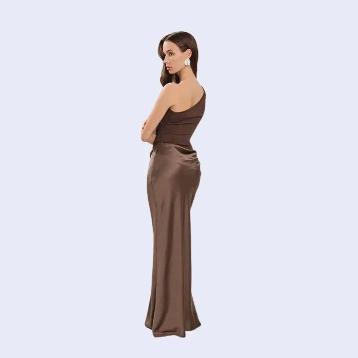 Femme de profil portant une robe longue asymétrique en satin couleur chocolat