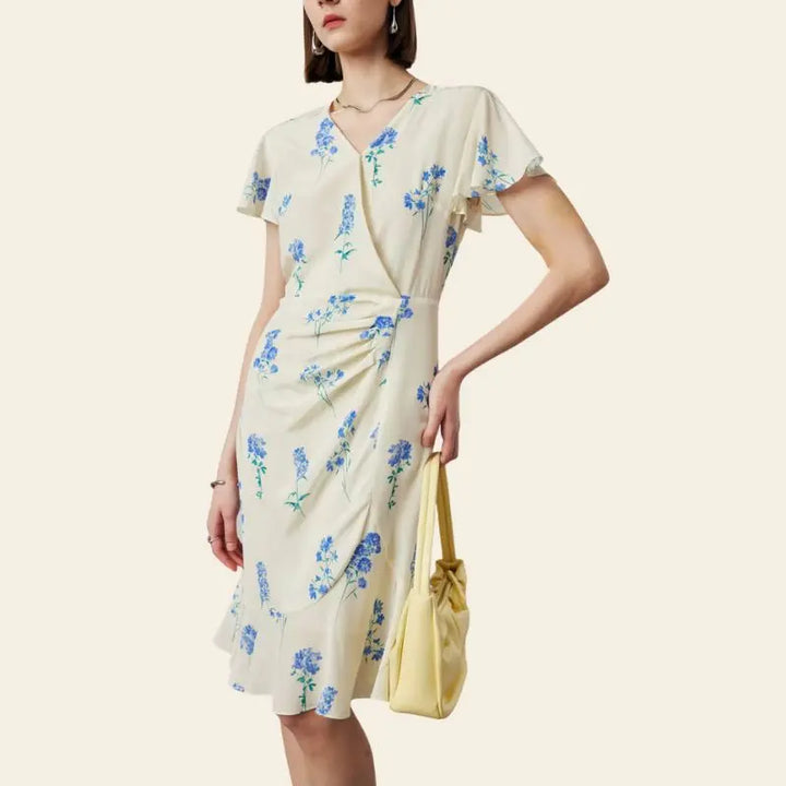 Mannequin portant une robe portefeuille mi-longue citron et fleurs bleues pure soie avec main sur la hanche