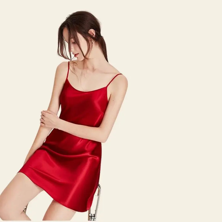 Mannequin assis portant une robe de nuit courte unie brillante en soie rouge
