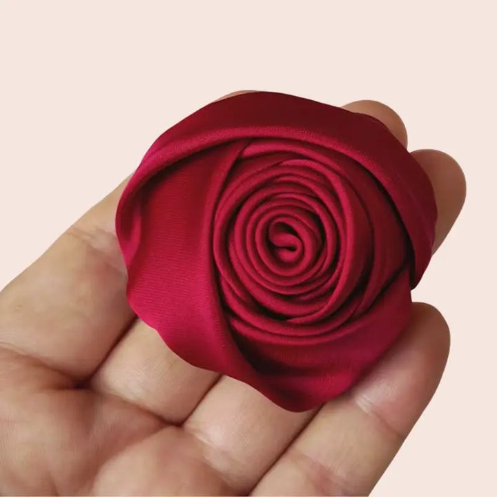 Main portant une roses fermée artificielle en satin de soie bordeaux