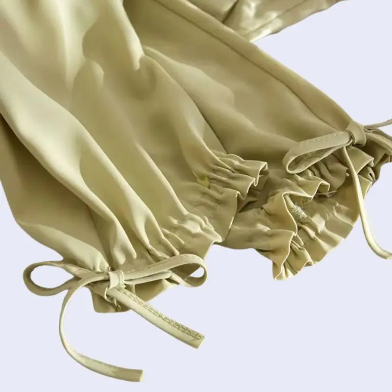 Zoom sur le bas d'un sarouel plissé poches et nœuds en satin jaune olive